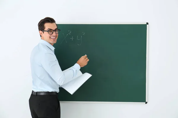 Guru muda dengan buku dekat papan tulis kosong di kelas. Ruang untuk teks — Stok Foto