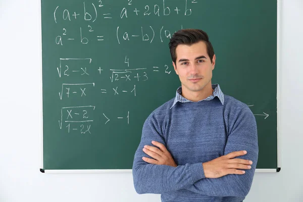 Młody nauczyciel w pobliżu tablica z formułami matematyki w klasie — Zdjęcie stockowe