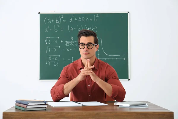 Young teacher working at table in classroom