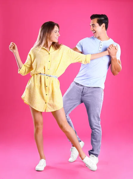 Hermosa pareja joven bailando sobre fondo rosa — Foto de Stock