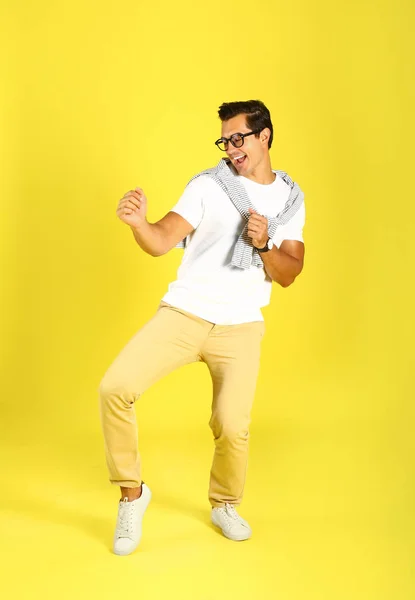 Pohledný mladý muž tančící na žlutém pozadí — Stock fotografie