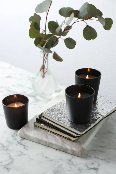 Composición con cuadernos, velas encendidas y ramas verdes sobre mesa de mármol — Foto de Stock