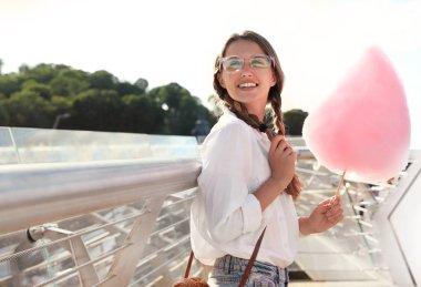 Güneşli bir günde dışarıda pamuk şekerli genç bir kadın. Metin için alan