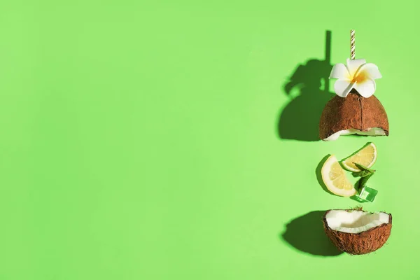 Kreatif gambar koktail musim panas yang dibuat dengan kelapa, lemon slice, mint, es dan jerami di latar belakang hijau, top view. Ruang untuk teks — Stok Foto