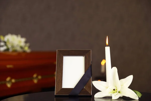葬儀場のテーブルの上に燃えるろうそくと白いユリと黒いフォトフレーム — ストック写真