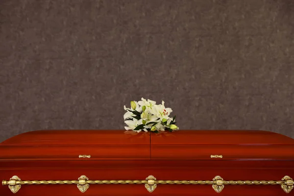 Cercueil funéraire en bois avec lis blancs au mur gris — Photo