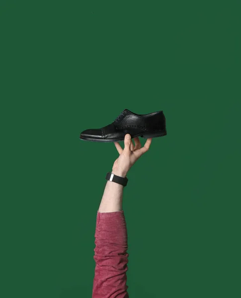 Homme tenant chaussure élégante sur fond vert, gros plan — Photo