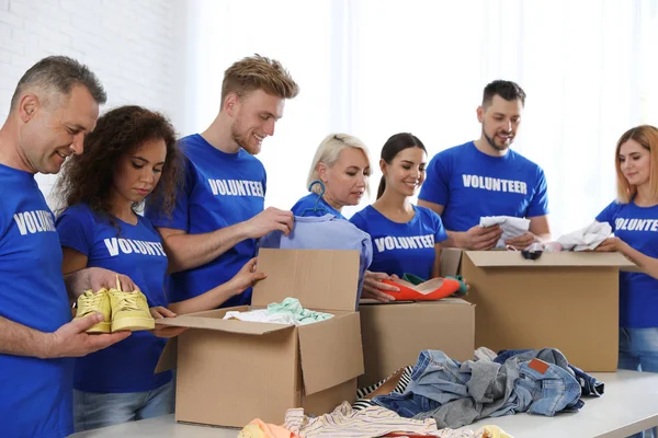 Equipo de voluntarios recogiendo donaciones en cajas interiores — Foto de Stock