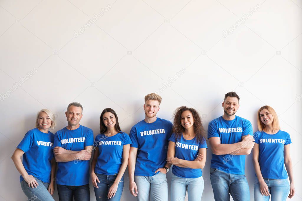 Team of volunteers in uniform on light background