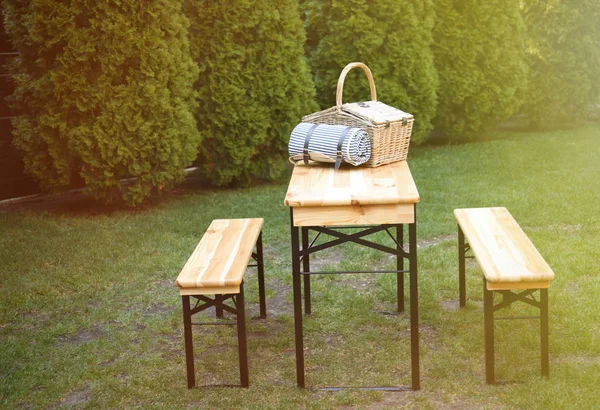 Rieten picknickmand en deken op houten tafel in Park — Stockfoto