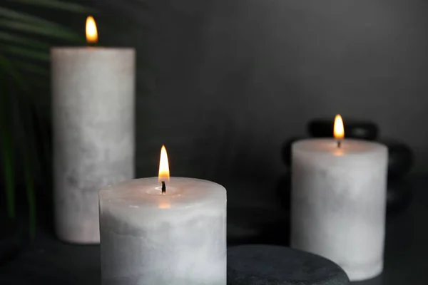 Bougies allumées, pierres de spa et feuilles de palmier sur fond gris — Photo