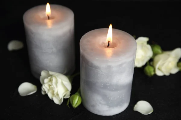 Queimando velas e belas flores na mesa preta — Fotografia de Stock