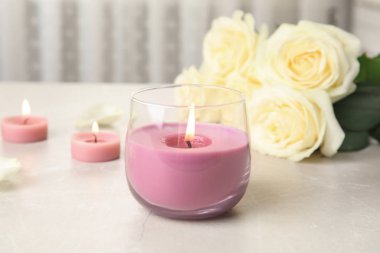 Cam tutucuda yanan mum ve ışık masasında güller