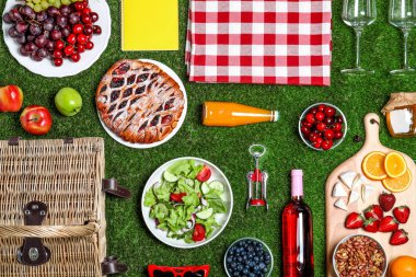 Yeşil çim üzerinde piknik sepeti ve ürünleri ile düz yatıyordu kompozisyon