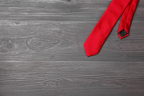 Stylish red silk necktie on dark grey wooden table, top view with space for text — Stock Photo, Image