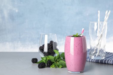 Gri masada lezzetli böğürtlen smoothie ve malzemeler cam. Metin için alan