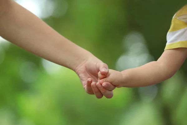 Mamma med sitt barn håller händerna tillsammans i parken på sommardag — Stockfoto