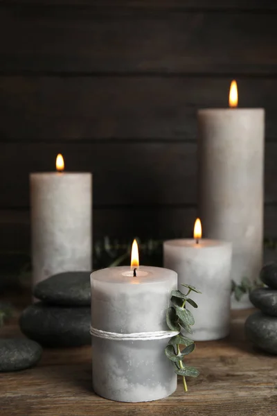 Composição com velas acesas, pedras de spa e eucalipto em mesa de madeira, espaço para texto — Fotografia de Stock