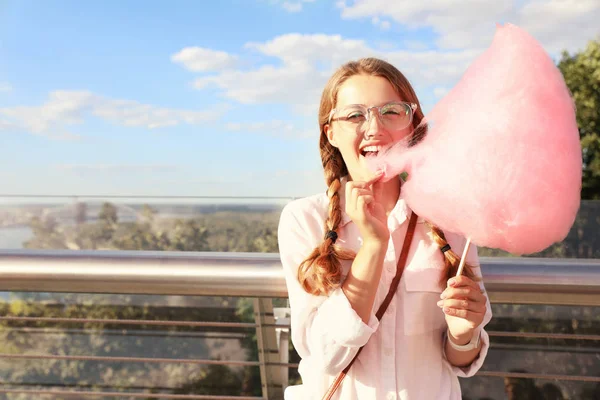 Mujer joven con algodón de azúcar al aire libre en el día soleado. Espacio para texto — Foto de Stock