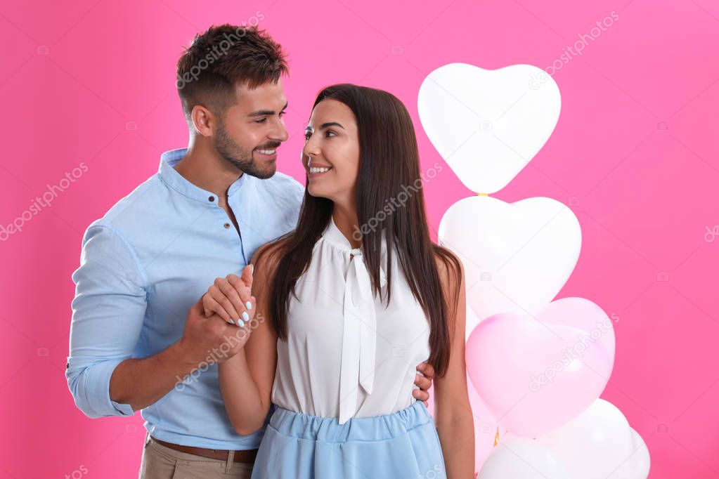 Young couple and air balloons on pink background. Celebration of Saint Valentine's Day