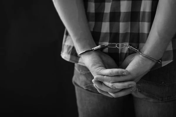 Преступник задержан в наручниках на темном фоне, место для текста. Черно-белый эффект — стоковое фото