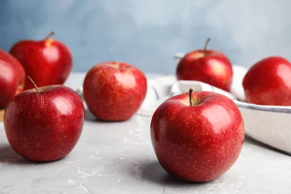 Pommes rouges juteuses mûres sur table grise sur fond bleu. Espace pour le texte — Photo