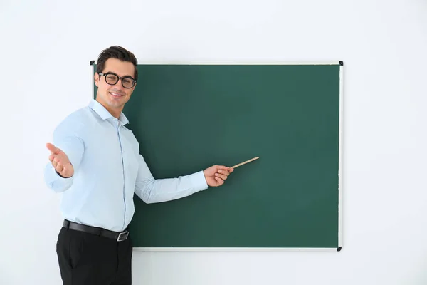 Guru muda dengan penguasa dekat papan tulis kosong di kelas. Ruang untuk teks — Stok Foto