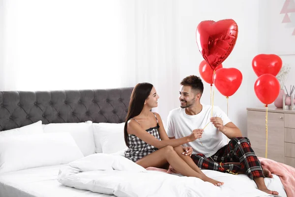 Junges Paar im mit Luftballons dekorierten Schlafzimmer. Feier zum Valentinstag — Stockfoto