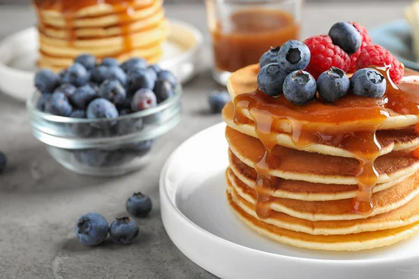 Pancake lezat dengan buah beri segar dan sirup di meja abu-abu — Stok Foto