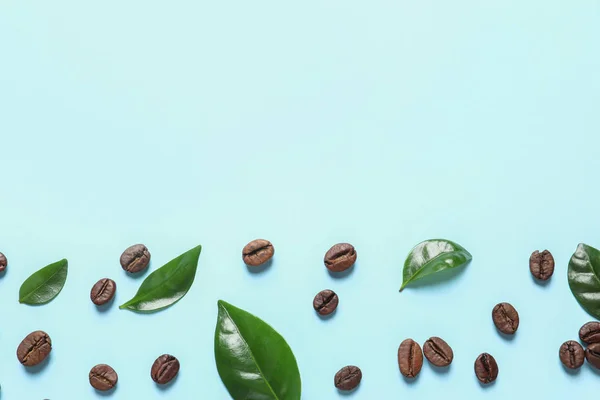 Fresh green coffee leaves and beans on light blue background, flat lay. Space for text