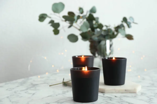 Brandende kaarsen en groene takken met Fairy lichten op marmeren tafel — Stockfoto