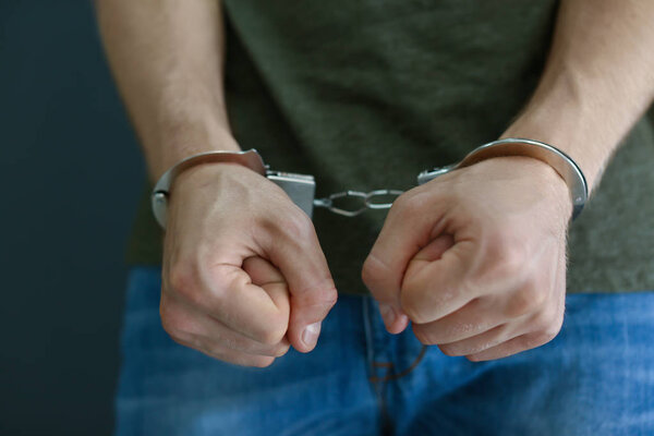 Man detained in handcuffs, closeup. Criminal law