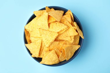 Açık mavi arka planda lezzetli Meksika nachos cips kase, üst görünüm
