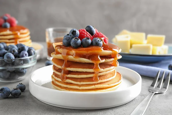 Deliciosos panqueques con bayas frescas y jarabe sobre mesa gris — Foto de Stock