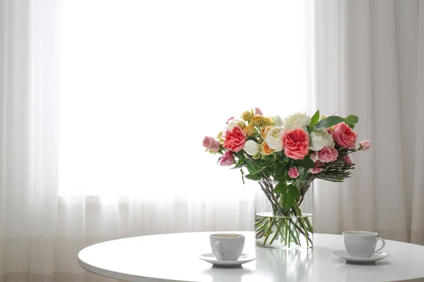 部屋のテーブルの上に美しい花の花束とコーヒーのカップと花瓶。テキスト用のスペース — ストック写真