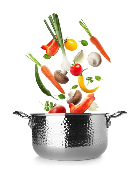 Många olika grönsaker som faller i potten på vit bakgrund — Stockfoto