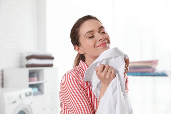 Happy young woman with clean shirt indoors. Laundry day — Stock Photo, Image