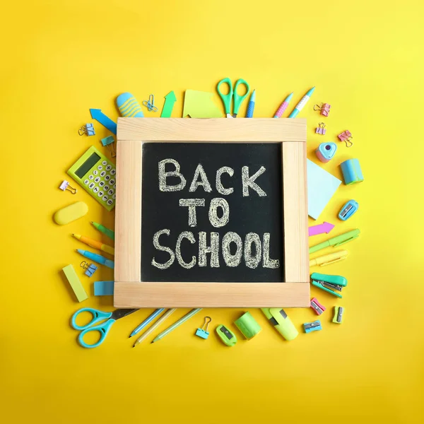 Schoolbord met zin "terug naar school" en verschillende briefpapier op gele achtergrond, platte lay — Stockfoto