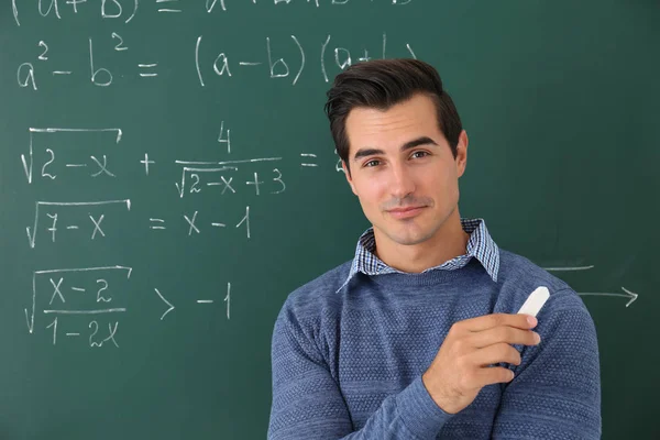 Ung lärare nära svarta tavlan med matematiska formler — Stockfoto