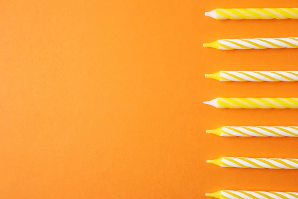 Velas de aniversário listradas coloridas no fundo laranja, vista superior com espaço para texto — Fotografia de Stock