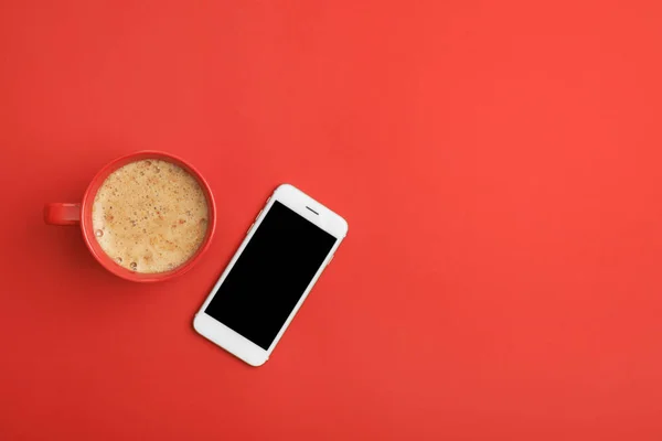 Cup of coffee and phone on red background, top view. Space for text — Stock Photo, Image