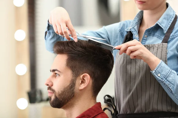 Barbeiro fazendo corte de cabelo elegante com tesoura profissional no salão de beleza — Fotografia de Stock