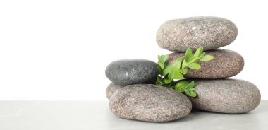 Beyaz arka plan karşı masaya spa taşları ve yaprakları yığını. Metin için alan