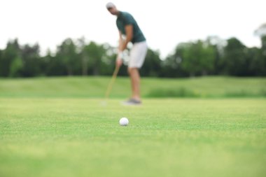 Yeşil sahada golf oynayan adam, top odakta. Spor ve eğlence