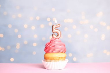 Şenlikli ışıklara karşı masada beş numaralı mum ile Doğum günü cupcake