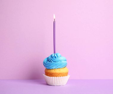 Mor arka plan üzerinde mum ile Doğum günü cupcake