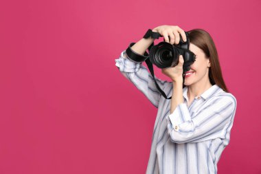 Profesyonel fotoğrafçı pembe arka planda fotoğraf çekiyor. Metin için alan