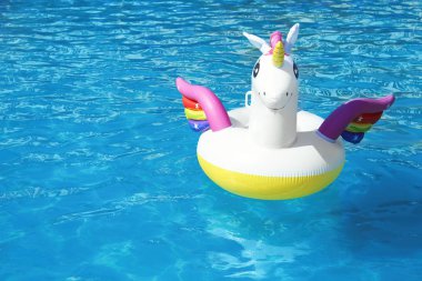 Güneşli bir gün yüzme havuzunda yüzen komik şişme Unicorn yüzük. Metin alanı