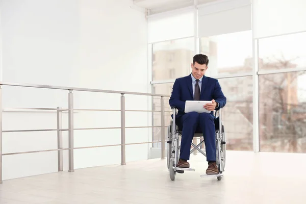 Junger Geschäftsmann im Rollstuhl nutzt Tablet in Fensternähe — Stockfoto