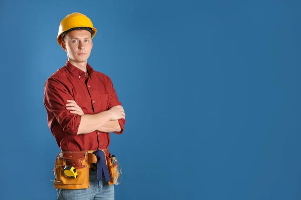 Hombre joven trabajador guapo en sombrero duro contra el fondo de color, espacio para el texto —  Fotos de Stock